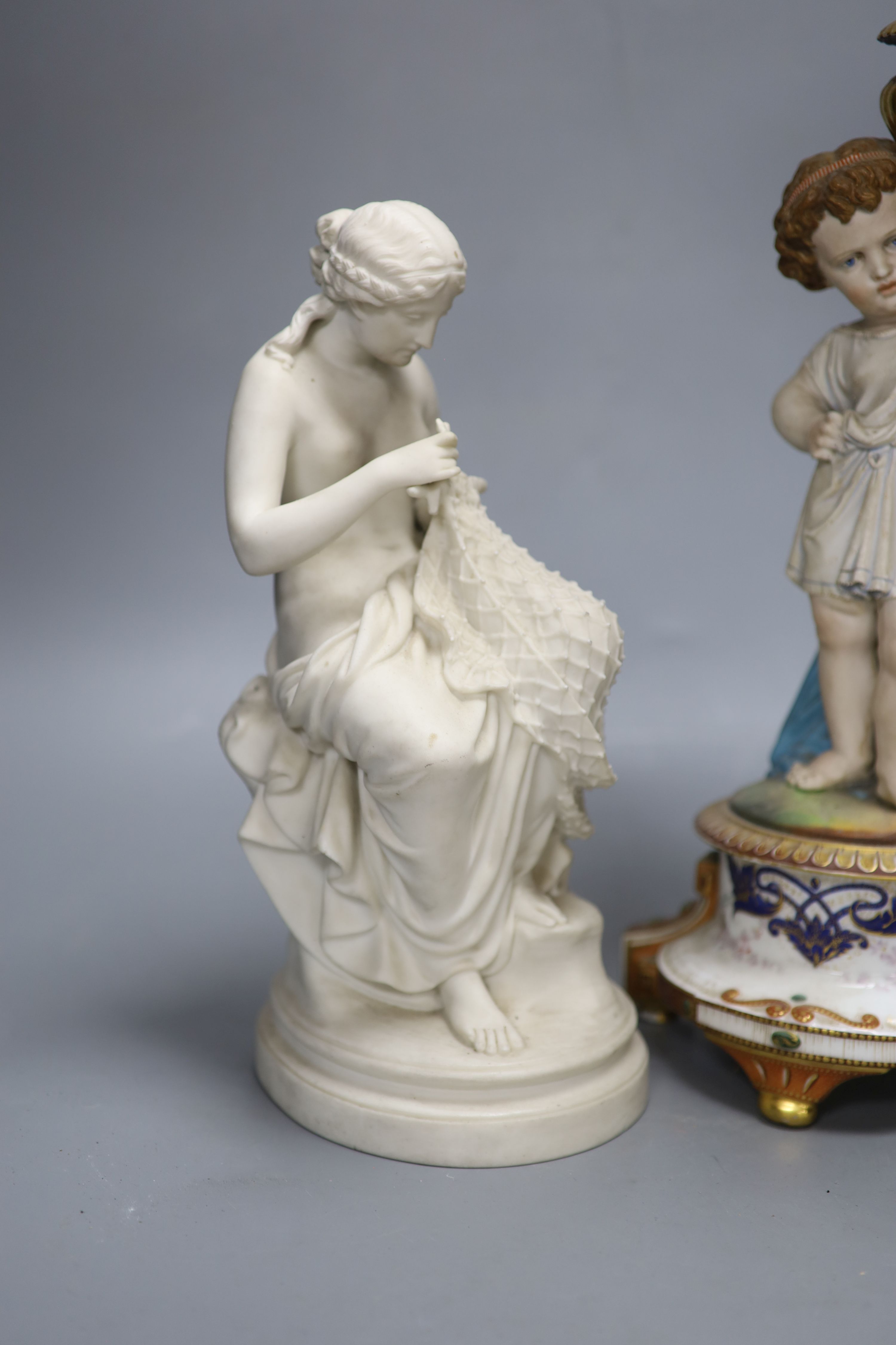 A Victorian Parian figure of a scantily clad fisher girl mending a net and a French trumpet shaped figural vase, tallest 49.5cm